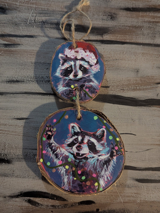 wood disc ornament consisting of 2 discs, each with vibrant raccoon on it, holding Christmas lights