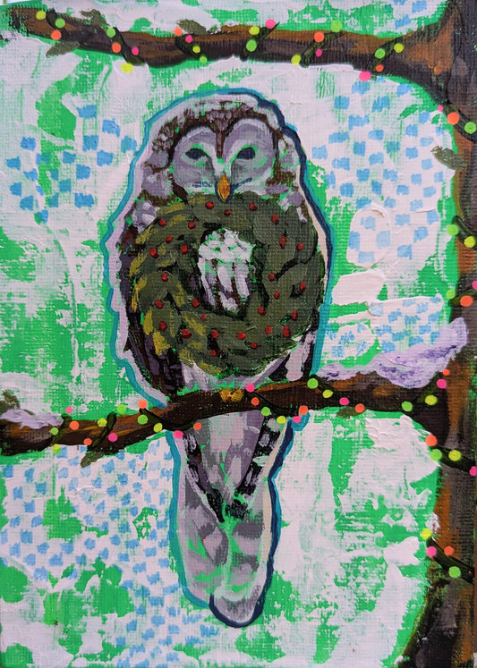 owl in tree holding wreath. tree is wrapped in vibrant Christmas lights. 