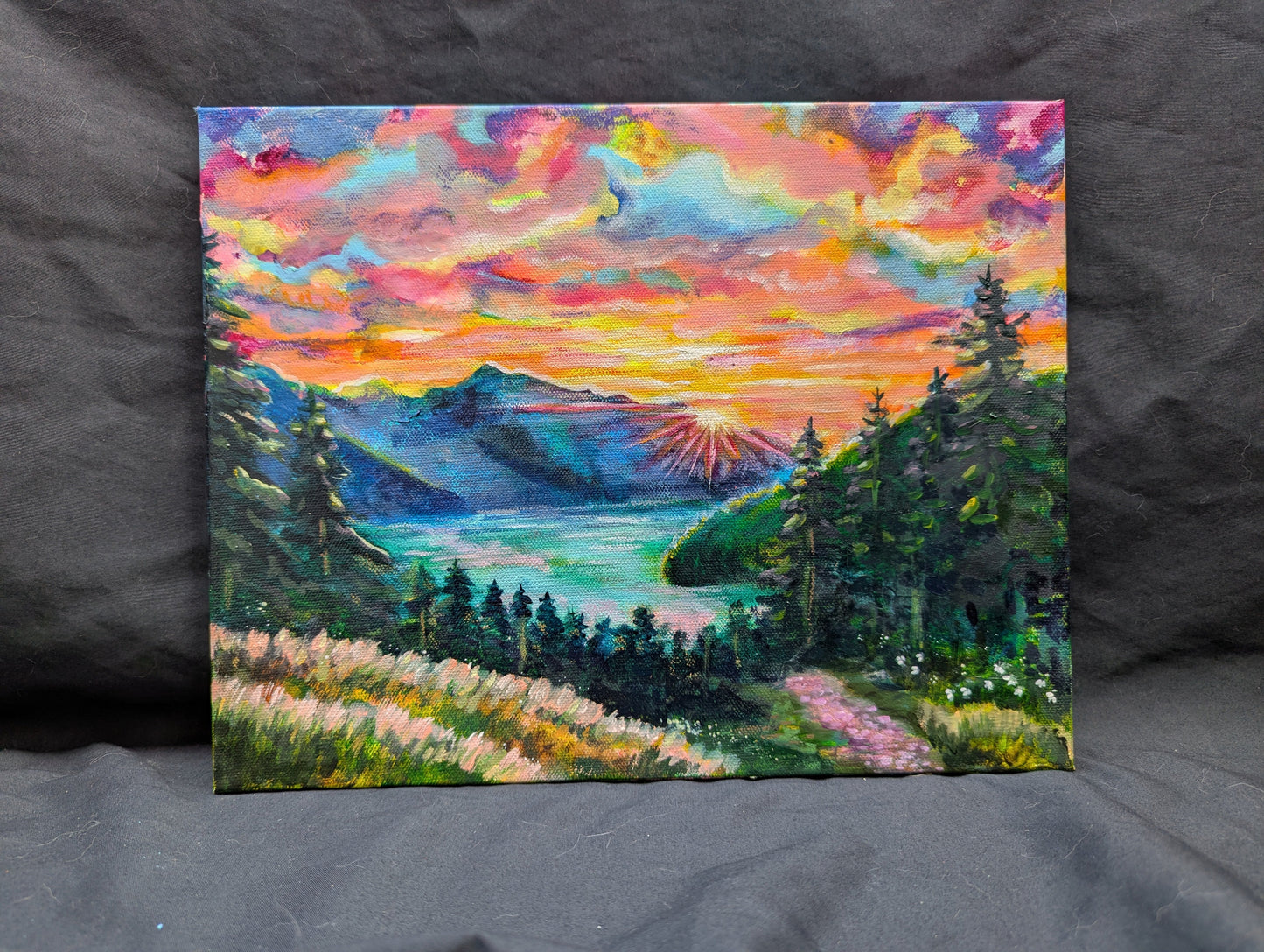 Colorful landscape painting of a sunset over a lake with trees and mountains.